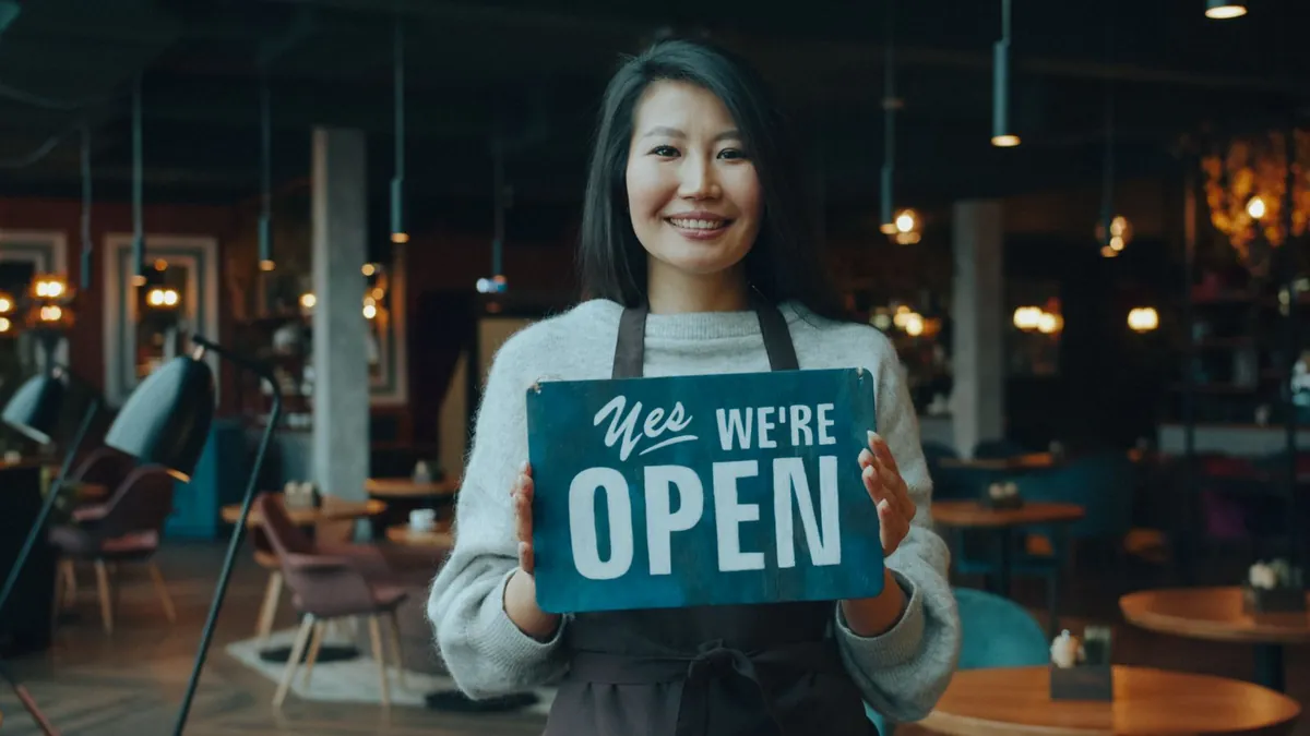 Restaurant owner holding a Yes, We’re Open sign