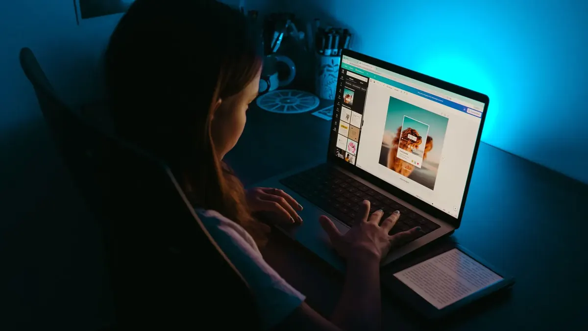 A person works on a laptop in a dark room