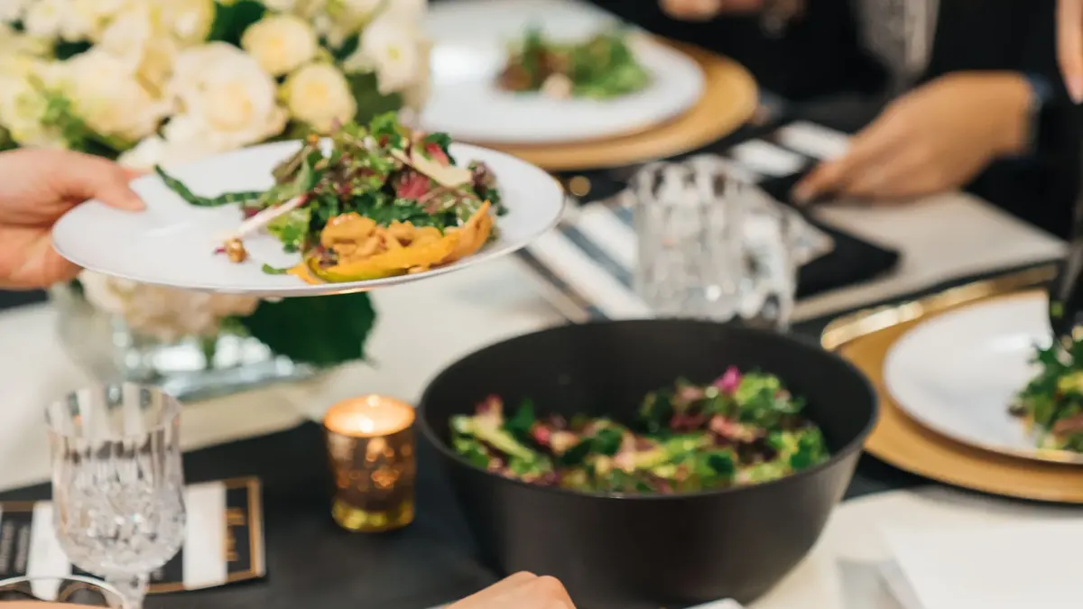 Guests share plates at a long preview-dinner table