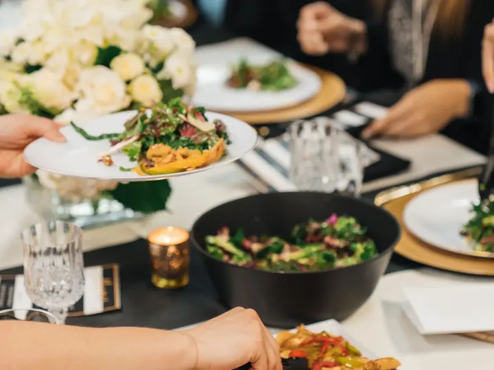 Guests share plates at a long preview-dinner table