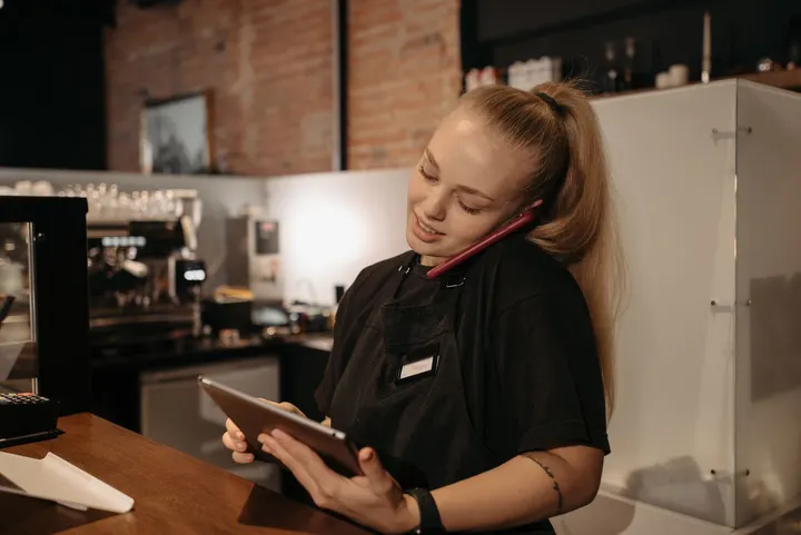 A restaurant host on the phone, holding a tablet