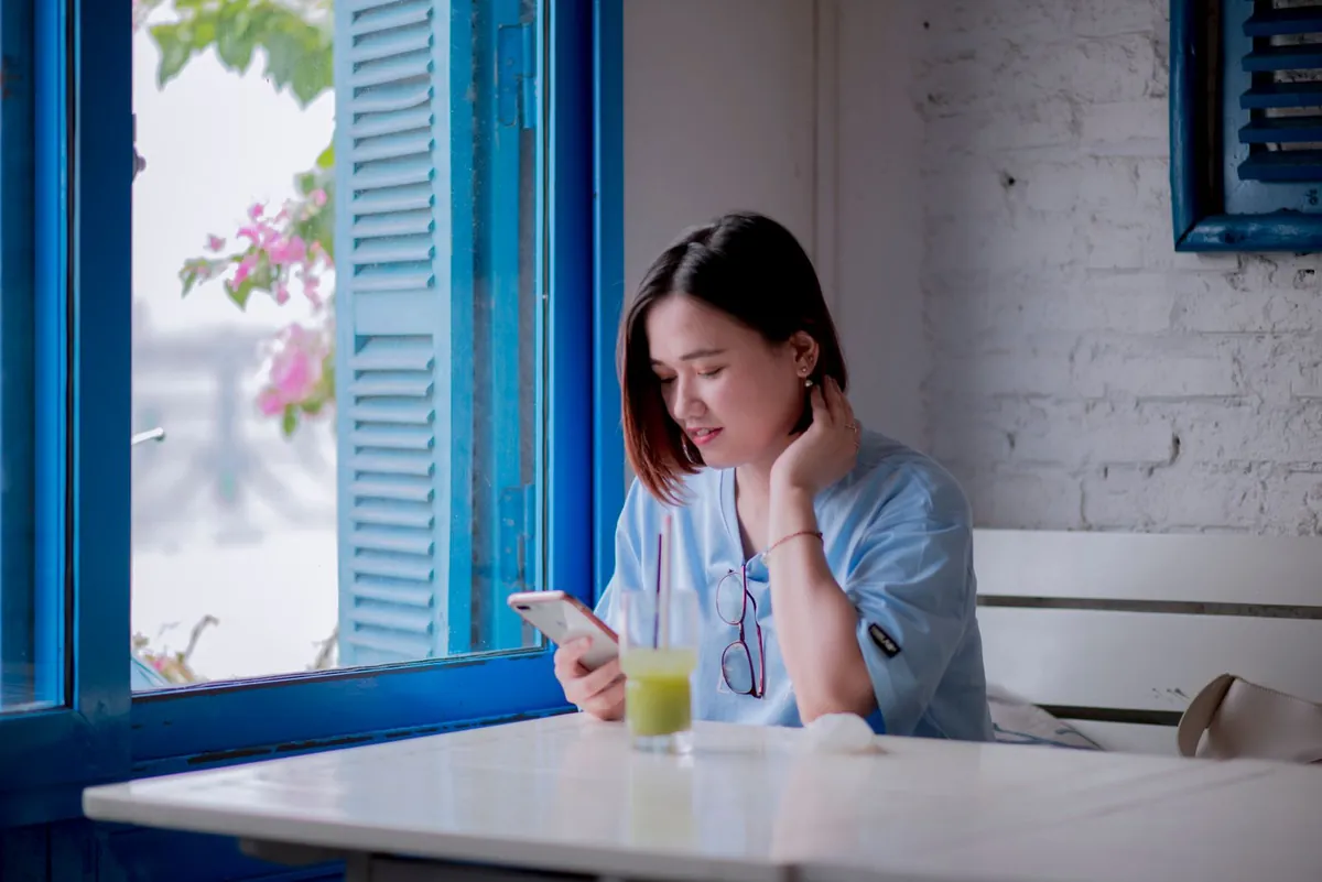 A woman reading her phone at a café window