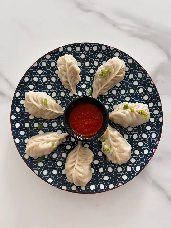 A plate of dumplings with dipping sauce